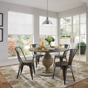 A dining space with two windows featuring motorized shades lowered halfway.