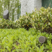 Image is of an outdoor Coastal Source speaker installed in the grass of a backyard.