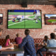 Patrons at a bar captivated by a football game on TV screens.