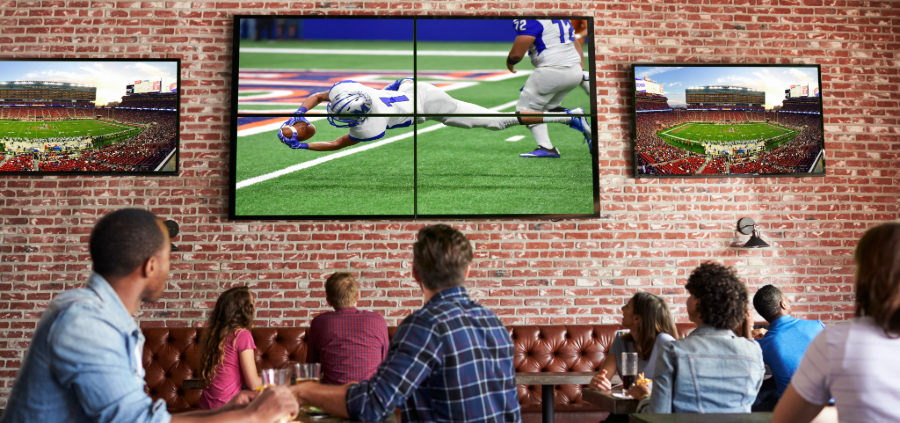 Patrons at a bar captivated by a football game on TV screens.