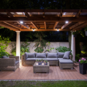 A pergola with a couch, a table, and motorized outdoor shades.