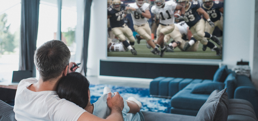 A couple snuggles in their private home theater while watching a football game.