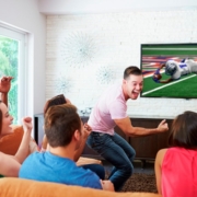 A group of friends watches an exciting football game at home.