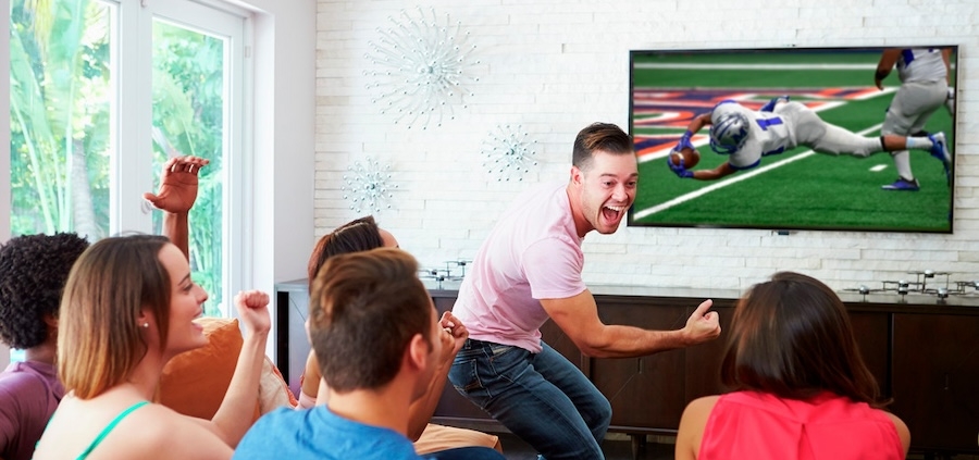 A group of friends watches an exciting football game at home.