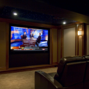 A media room with theater seating facing a projector screen.